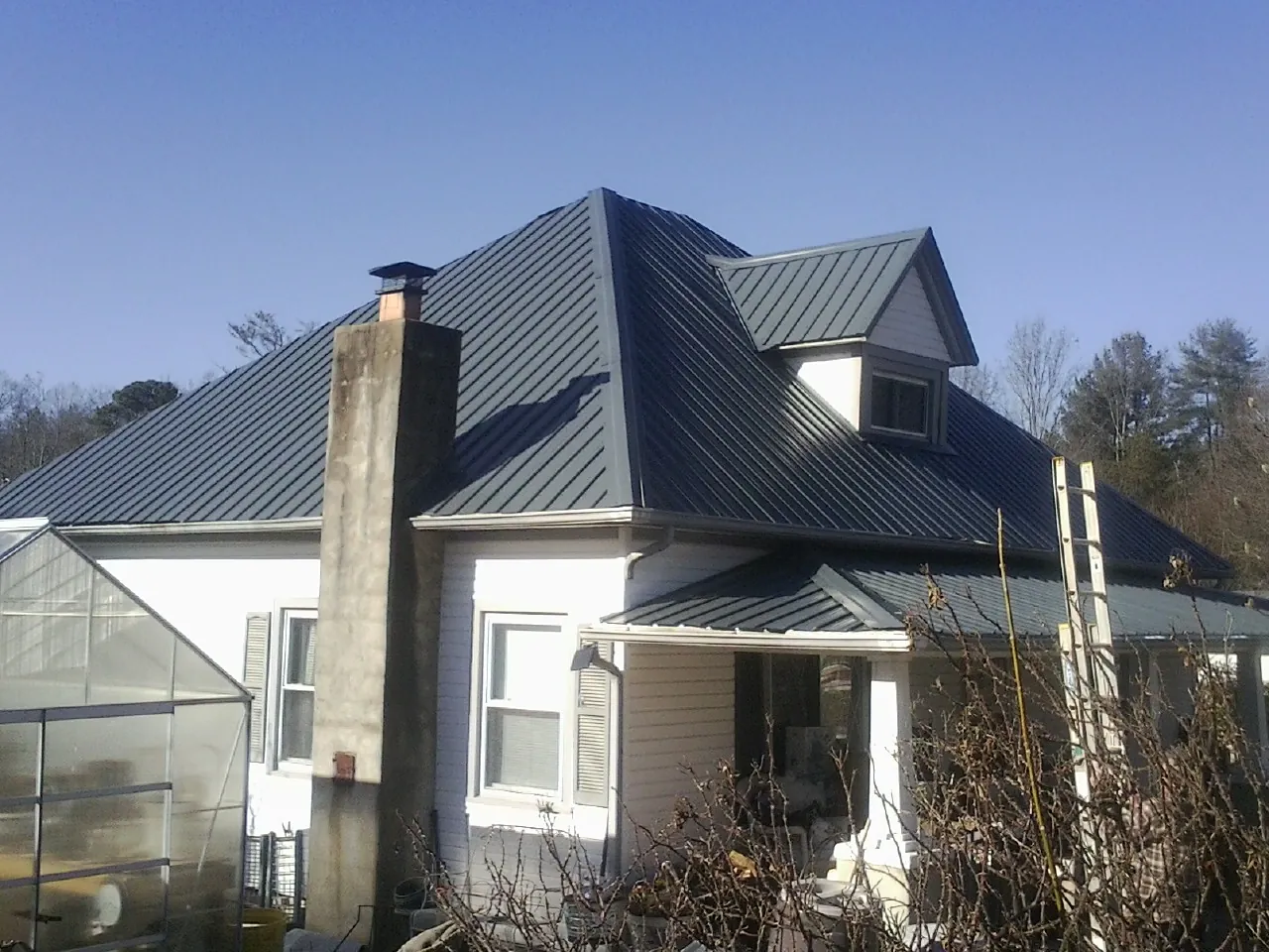 Dark blue standing seam metal roof on a white farmhouse with dormer — Slate & Tile Roof Repair by Roofing Brothers in Marine On Saint Croix