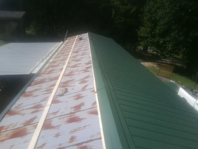 Old rusted panels beside newly installed green metal roofing — Wind Damage Roof Repair by Roofing Brothers in Marine On Saint Croix