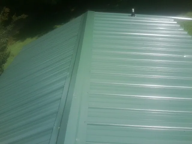 New green metal panels meeting at the ridge of a roof — Flat Roof Repair work by our crew in Marine On Saint Croix