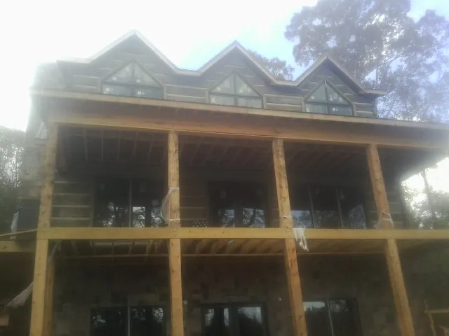 Dormers and porch framing on a large log home under construction — Roof Coating work by our crew in Marine On Saint Croix