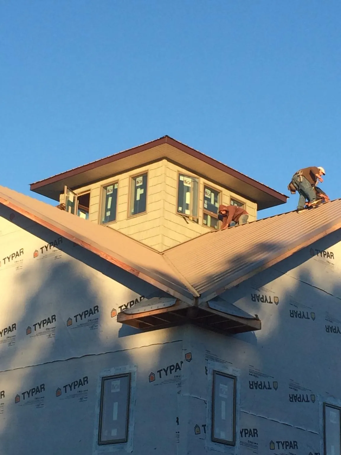 Roofers working around a rooftop cupola on a new metal roof at sunset — Roof Waterproofing in Marine On Saint Croix by Roofing Brothers